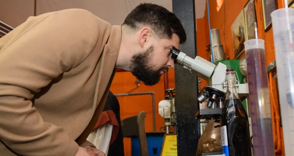 Batemans Brewery Tour - Man inspecting Sample through Microscope in Brewhouse